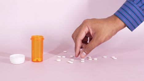 White--medical-pills-spilling-on-pink-,