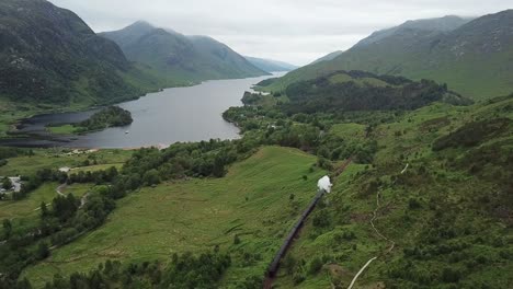 aerial follows steam train along loch shiel in scottish highlands