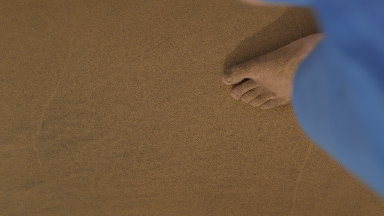 다리와 은 벌거벗은 발이 모래 해변에서 천천히 고 바다 물 파도에 다가오고 있습니다.