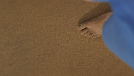 legs and wet bare feet walking slowly on sandy beach approaching an ocean water waves