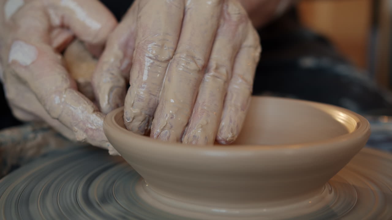 Hands shaping a bowl on a pottery wheel