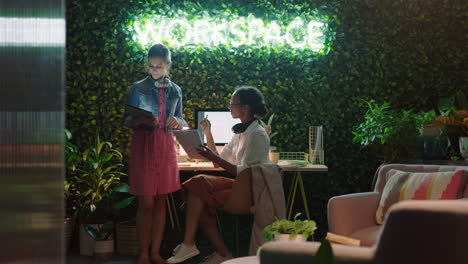 personas de negocios que trabajan hasta tarde usando computadoras tablet líder de equipo mujer compartiendo ideas mostrando a un colega apuntando a la pantalla discutiendo información de proyectos en una oficina moderna por la noche