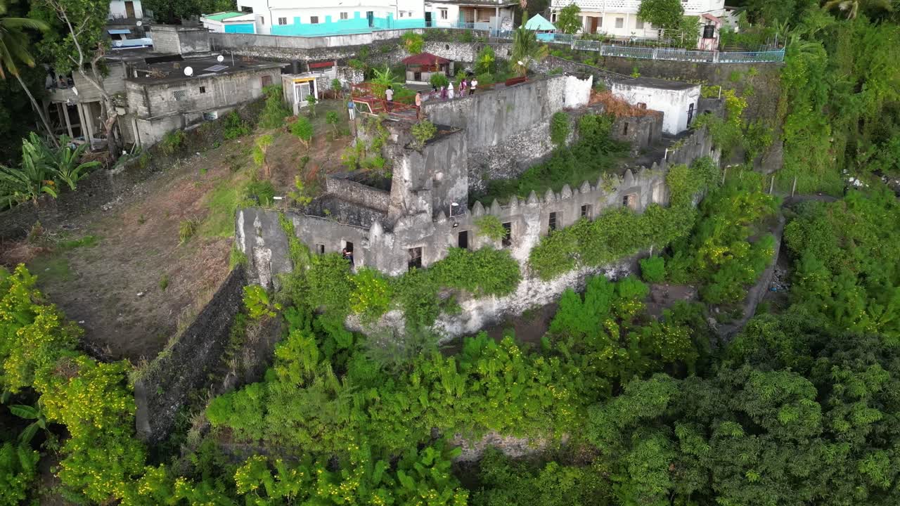 드론은 코모로 섬의 안주안 섬에 있는 오래된 고대 돌 성 주변을 회전합니다. 아프리카, 인도양, 순수한 자연에서 여행 목적지.