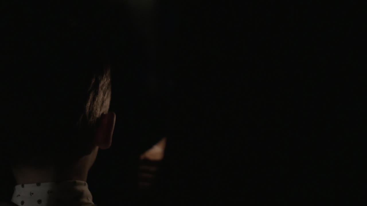 niño y mamá llevando pastel de cumpleaños con vela en la oscuridad