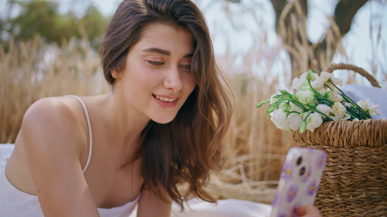 Young brunette making selfie holding mobile phone at field close up. Lady laying