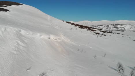 Winter-mountainscape-with-frozen-snowdrift-overhanging-cliff,-mini-avalanche