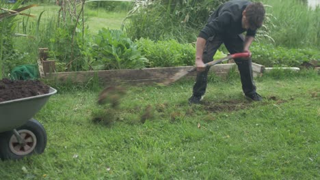 young man working removing topsoil grass layer from garden