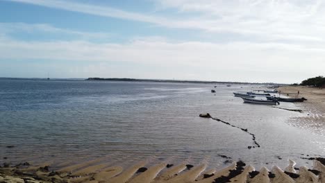 Calm-Afternoon-at-Sanur-Beach,-Bali,-Indonesia,-White-Sand-and-Blue-Sky,-Dock-of-Stones-and-Boats-in-the-Touristic-Destination-of-the-Island-of-Gods