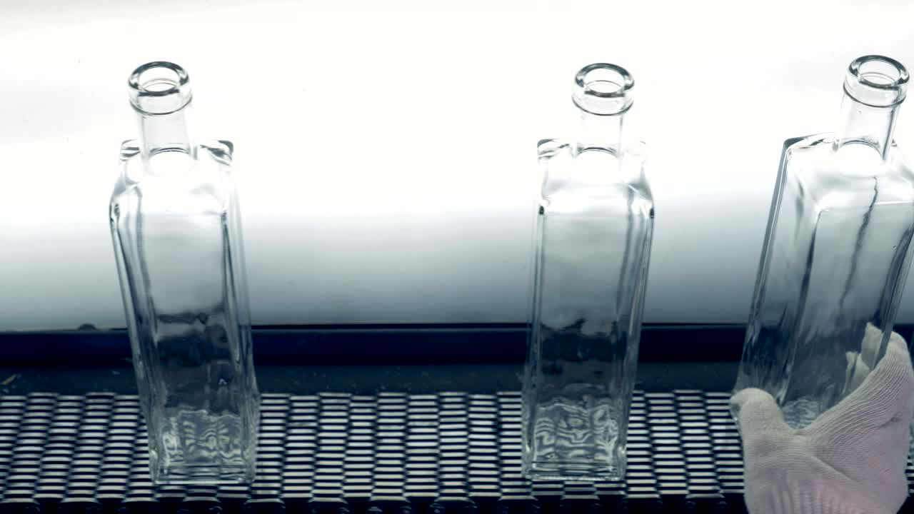 공허 한 병 들 은 컨베이어 를 따라 이동 하는 동안 공장 노동자 에 의해 돌려진다