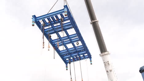 crane boom lifting metal frame at construction site