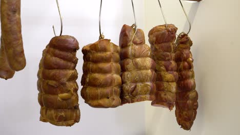 Large chunks of smoked ham hocks hanging on hooks