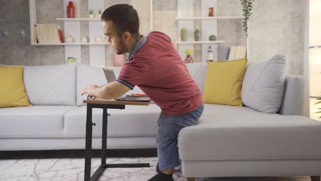 Junger-Männlicher-Student-Mit-Kleinwuchs,-Der-Zu-Hause-Mit-Einem-Laptop-Lernt.