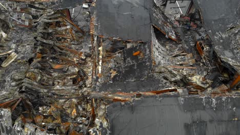 aerial flying backwards over industrial building destroyed by fire