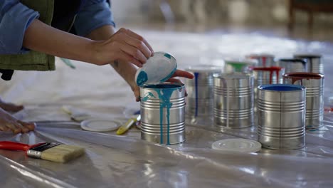 manos femeninas en el taller de estudio abrir diferentes colores de pintura en el frasco, preparar suministros