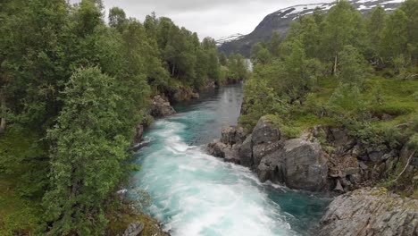 Beautiful-river-cascading-down-mountainside,-aerial-dolly-view-downstream