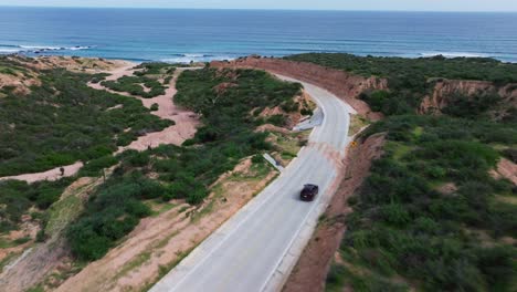 drone descends tilting up to reveal epic cabo pulmo beach as suv races down road