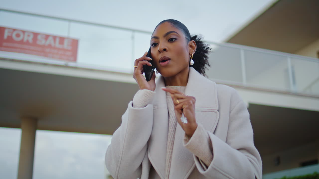 Property agent talking phone at house for sale. Serious african american discuss
