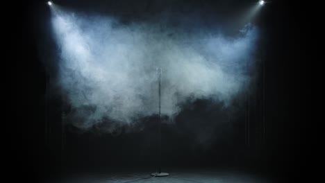 a vintage metal microphone looms against a black studio background of smoke. the smoke dissipates and a microphone appears shining in the studio light