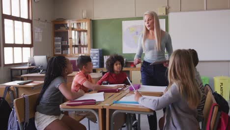 female teacher teaching group of kids using digital tablet