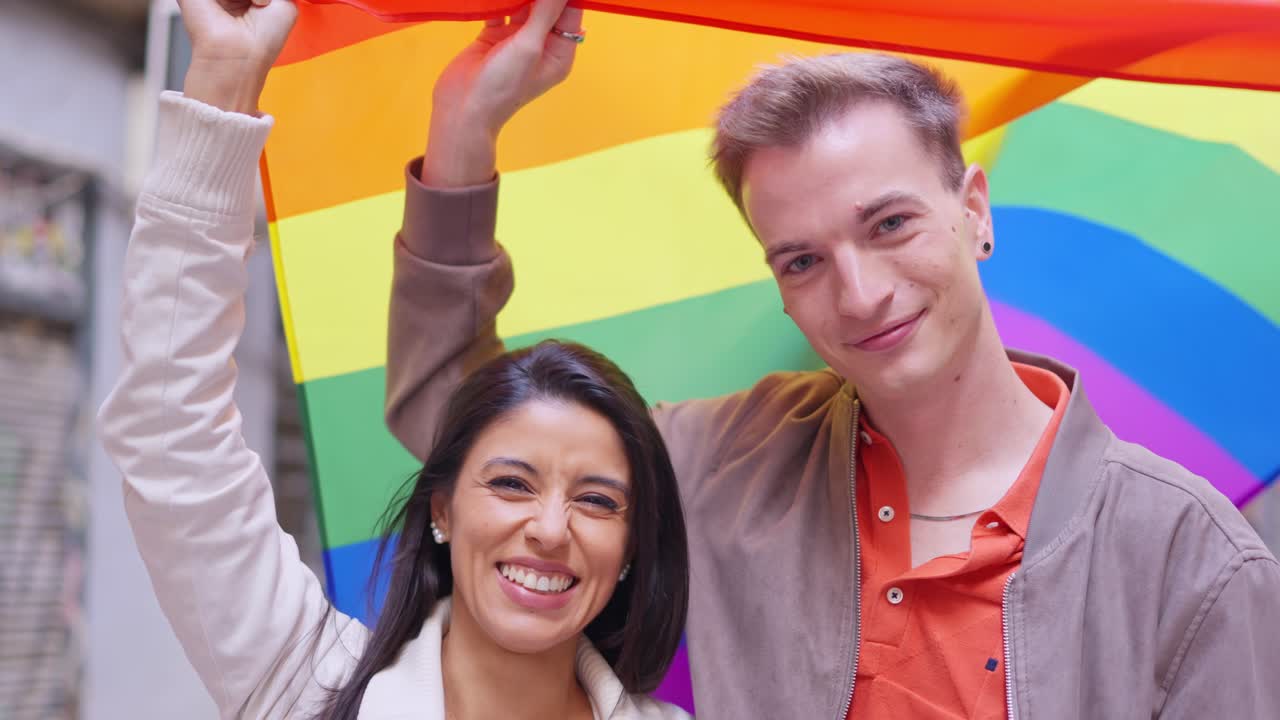 Happy Young Couple Holding Rainbow LGBTQ+ Flag on Street