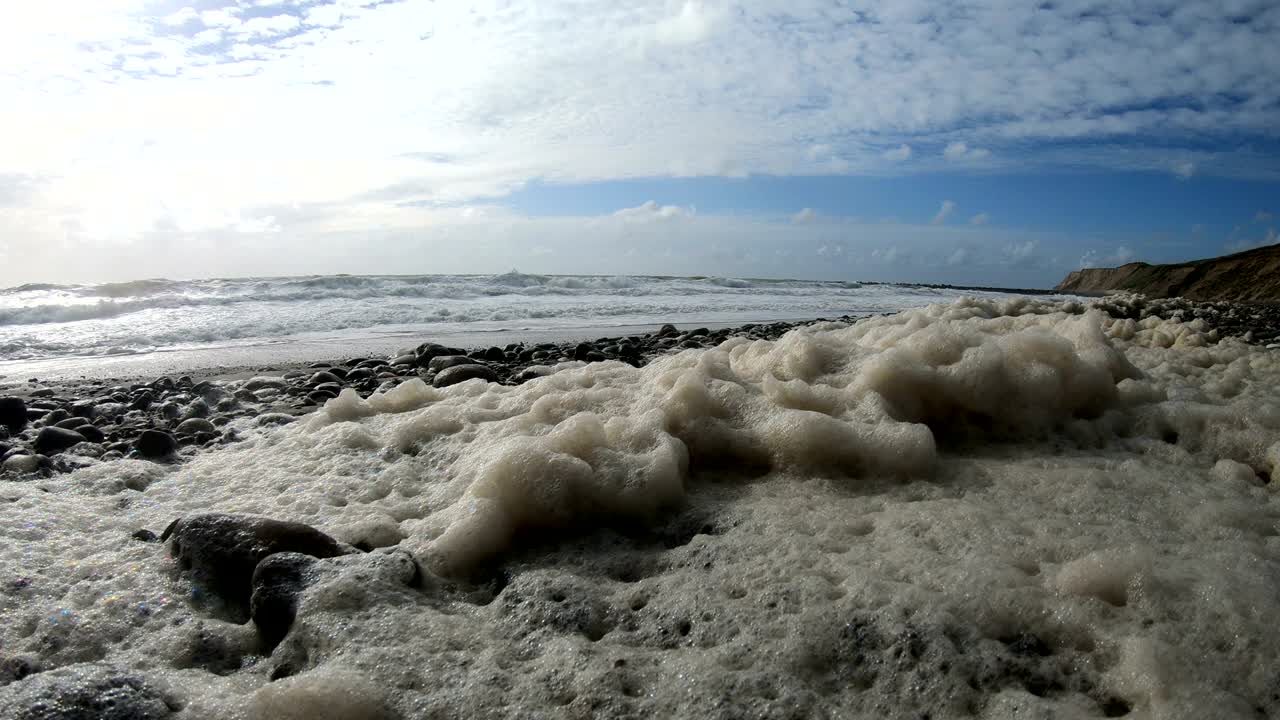 пена водорослей в шторме на пляже, песчаный пляж с волнами, северное море, ютландия, сондервиг, дания, 4к