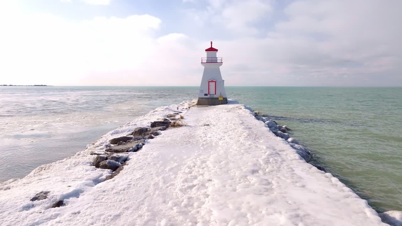 Winter scene of a snowy pier leading to the Southampton lighthouse under a cloudy sky