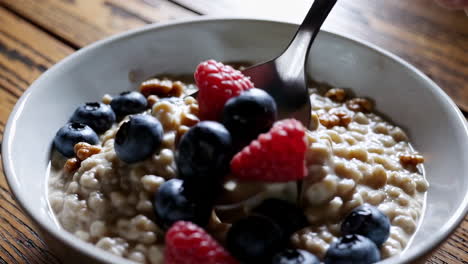 adding berries and walnuts to a bowl of oatmeal