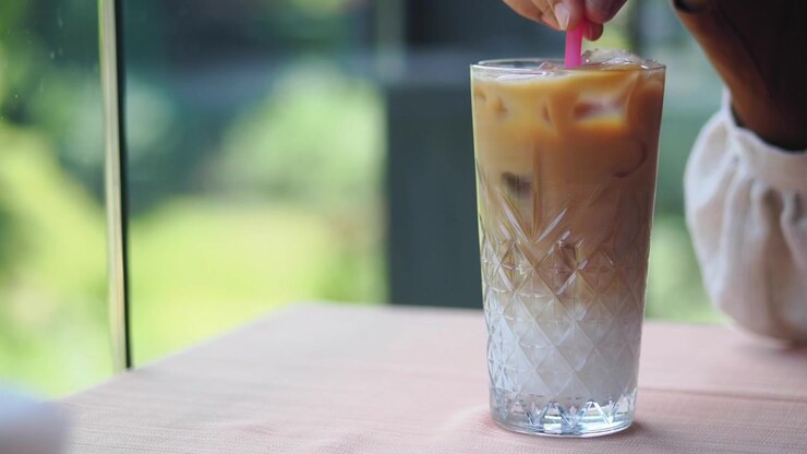 Persona che mescola un caffè freddo in un bicchiere in un bar