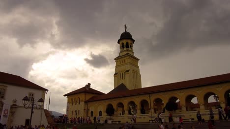 establishing shot of church with a crowd of people walking infront of it in alba iulia , citadel alba-carolina