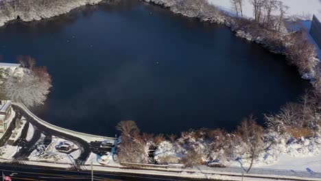 an aerial view over a pond on a sunny day after a snow fall