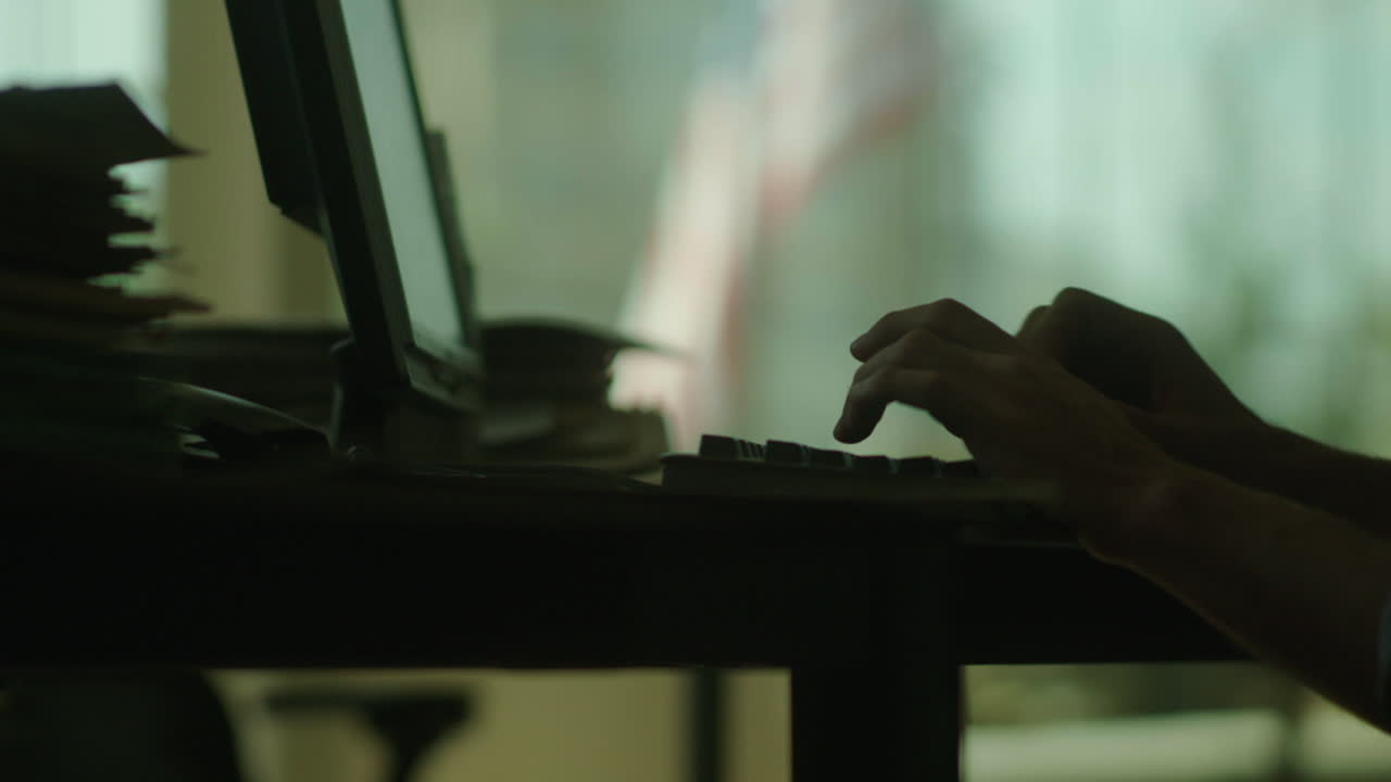 Person working on computer with paperwork