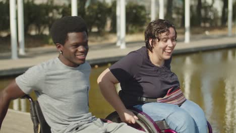 young cheerful couple using wheelchairs wheeling through puddle