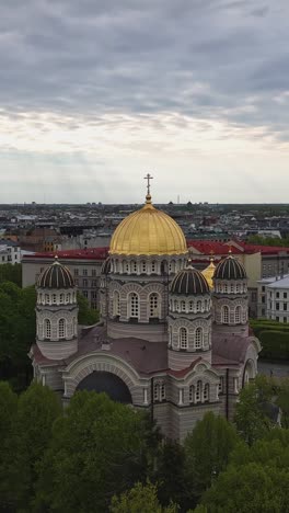 the golden-domed nativity of christ cathedral rises above the trees in the heart of riga, latvia - vertical shot
