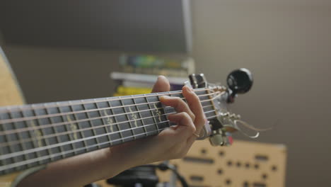 imágenes de los dedos de una mujer tocando una guitarra acústica en un estudio