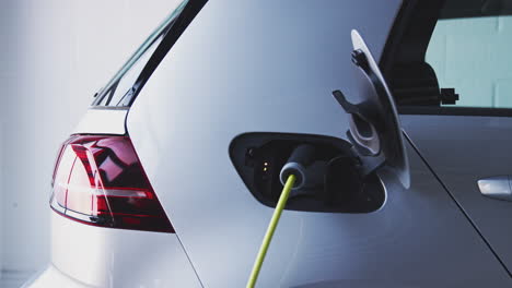 cerca de la mano conectando el cable de alimentación al coche eléctrico antes de tomar las bolsas de tela del maletero