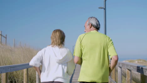 man and woman in sportswear jogging along wooden path outdoor