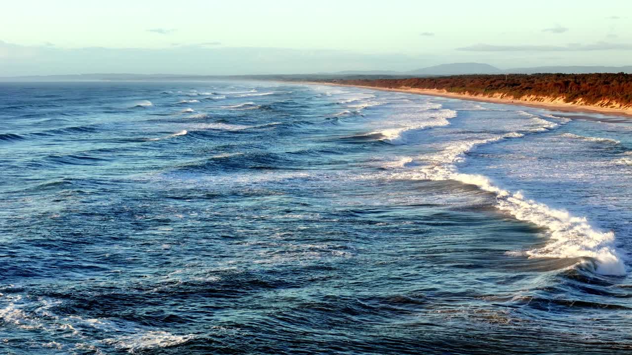 olas escarpadas que crecen a lo largo de una vasta playa, la interfaz dinámica de mar y tierra bajo el cielo abierto