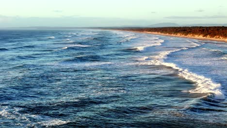 Olas-Escarpadas-Que-Se-Elevan-A-Lo-Largo-De-Una-Vasta-Playa,-La-Interfaz-Dinámica-Del-Mar-Y-La-Tierra-Bajo-El-Cielo-Abierto