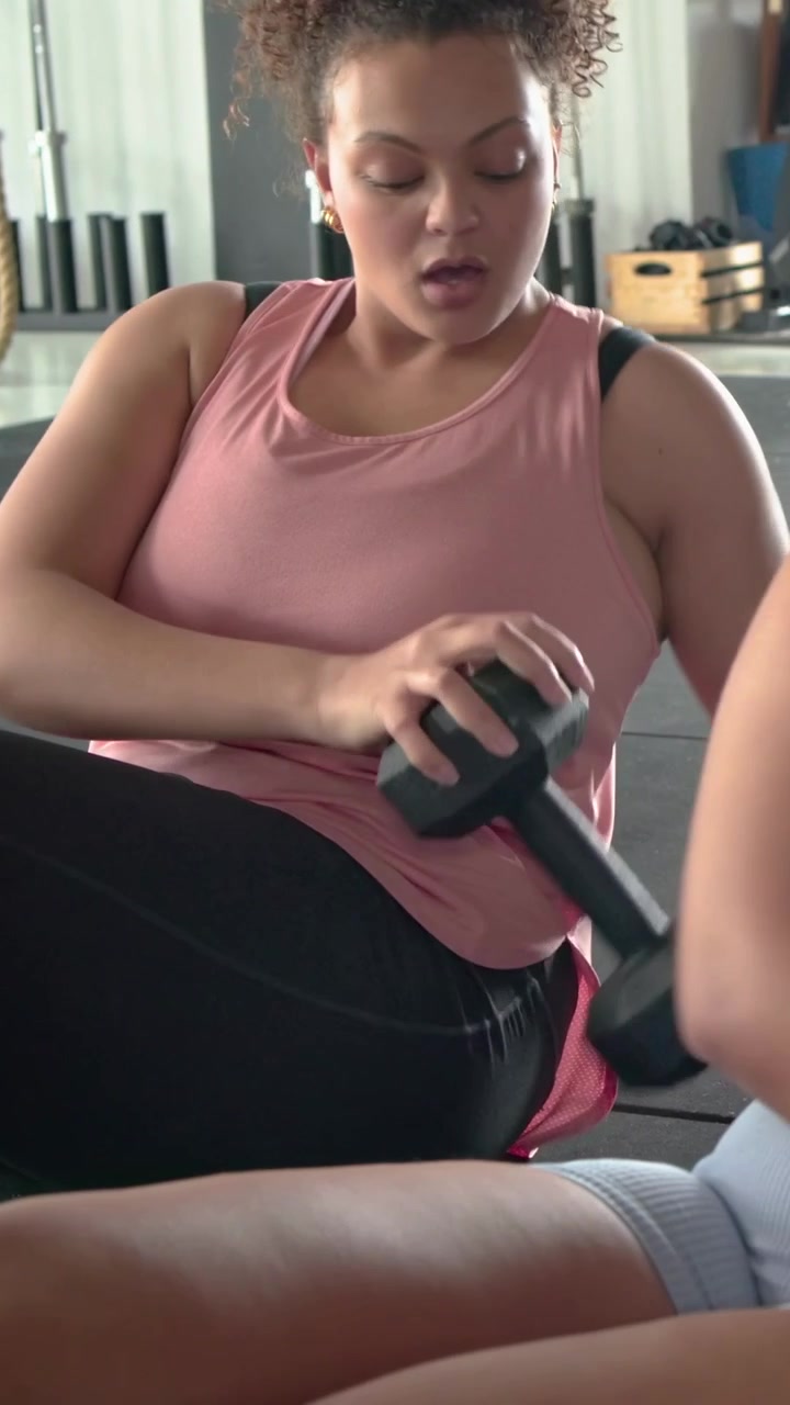 Video verticale: Donna con top rosa che tiene un kettlebell, si torce sul tappetino, allena il core e unisce le mani.