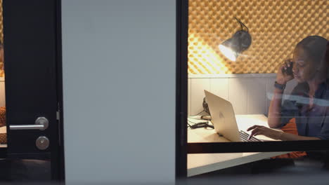 businesswomen working late in individual office cubicles using laptop and digital tablet