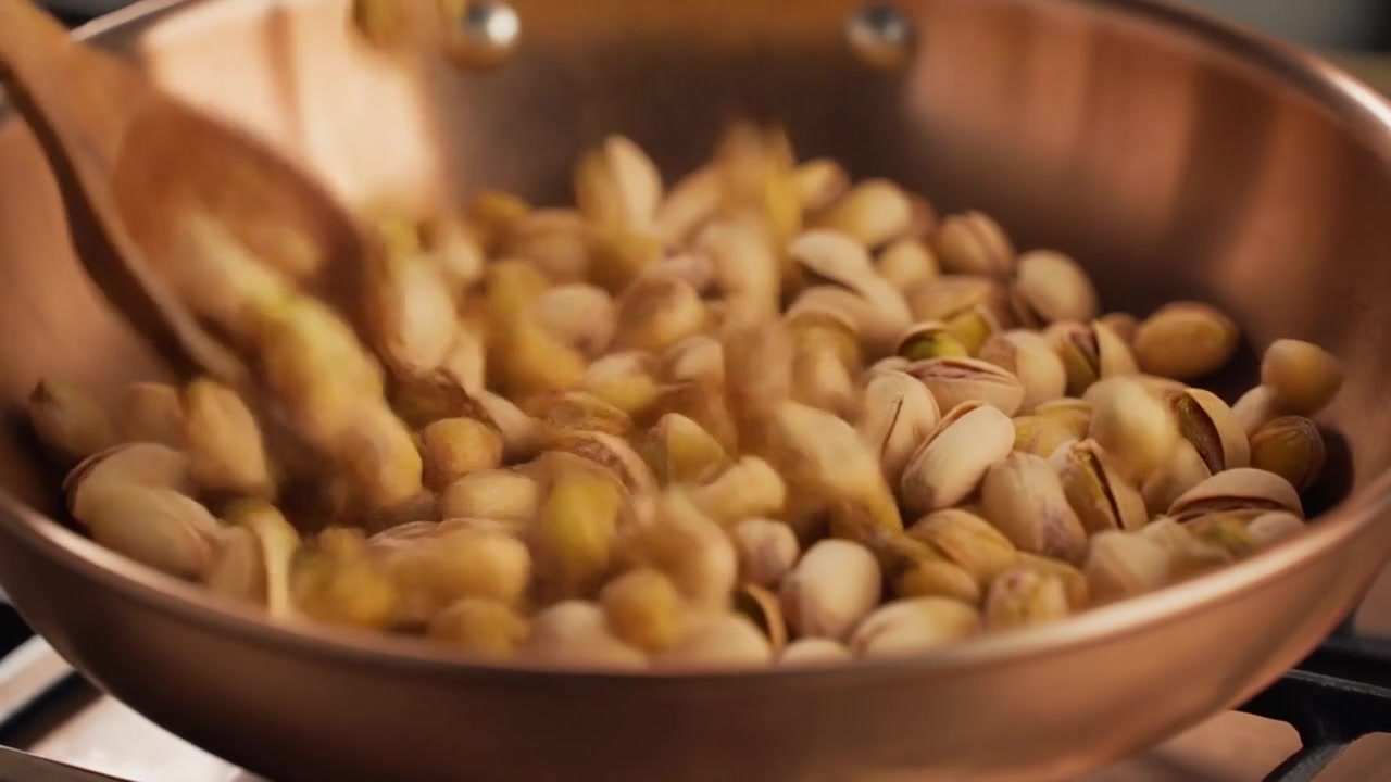 Chef che tosta pistacchi in una padella di rame