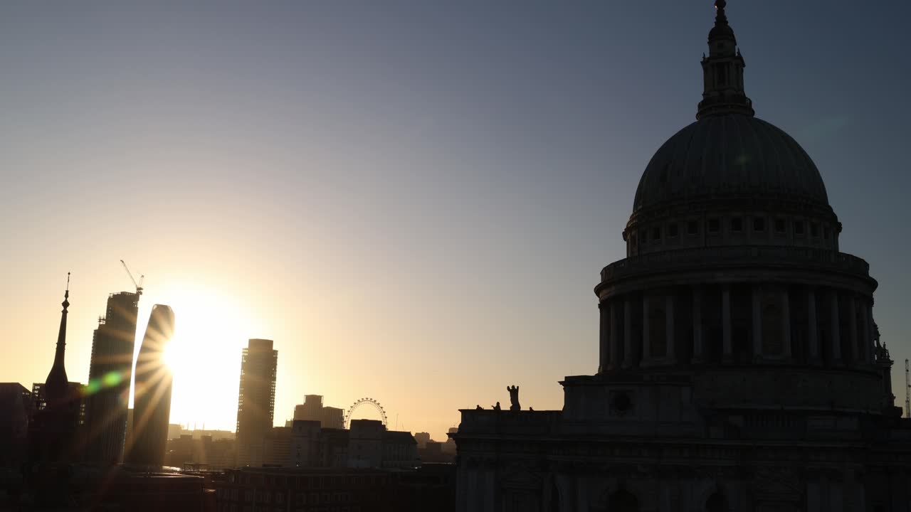 Skyline di Londra al tramonto con silhouette di edifici, ampia inquadratura di contesto.