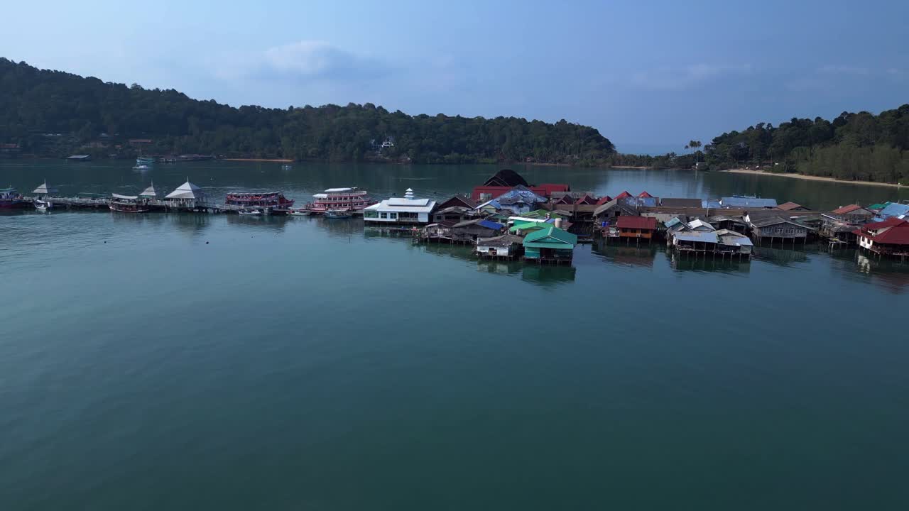 Bang Bao Pier floating village in Koh Chang island, Thailand, showing colorful houses and boats sailing in turquoise water. Gorgeous aerial view flight ascending drone