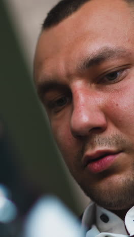 concentrated man wearing black suit with white shirt looks down preparing for festive ceremony in light room low angle shot closeup