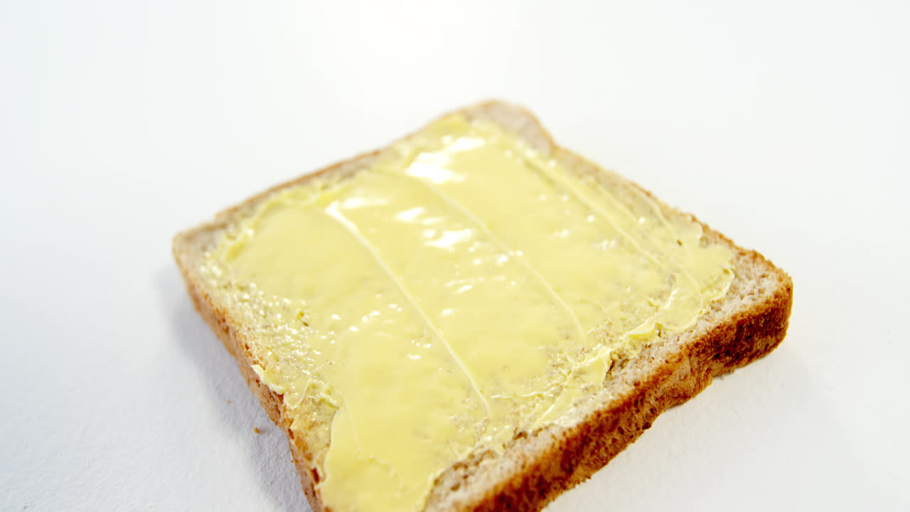 Butter spread on bread slice against white background