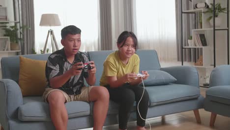 asian children with joystick game play video game on tv, boy celebrating victory and girl disappointed