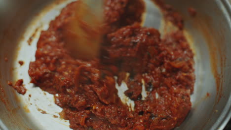 close-up of stirring rich tomato-based sauce in pan