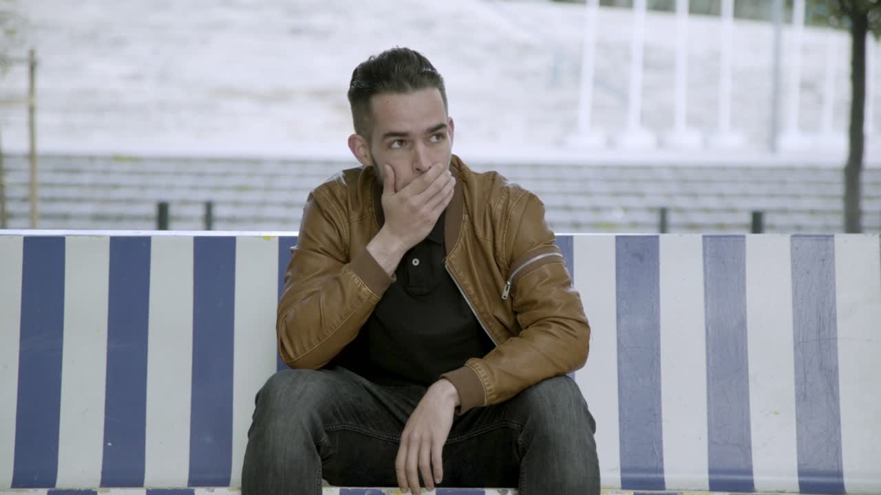 나무 벤치 에 앉아 얼굴 을  ⁇ 는 화가 난 청년