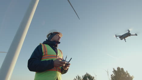 energy engineer inspecting wind farm with drone