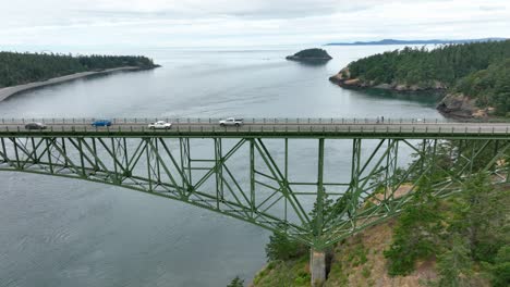 Drone-perspective-of-trucks-driving-across-green-steel-bridge